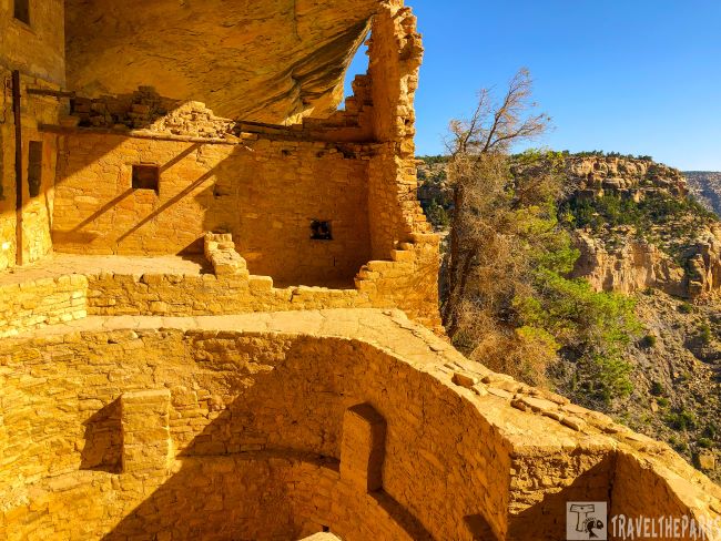 Ancient cliff dwelling in Mesa Verde with stone walls and canyon in the background.