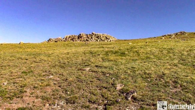 A grassy hill featuring scattered rocks, showcasing the natural beauty of Rocky Mountain National Park.