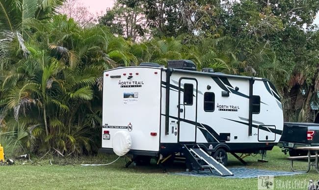 North Trail travel trailer parked on grass near palm trees at Trail Lakes Campground