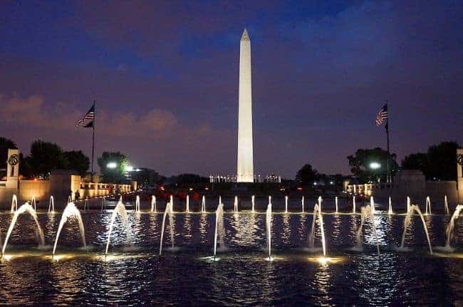 The Washington Monument at night with lit fountains in front.