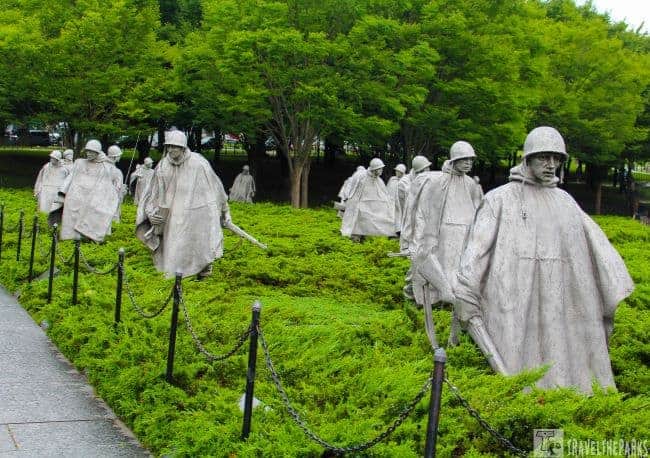 Korean War Memorial Statues of soldiers walking through greenery, surrounded by trees.