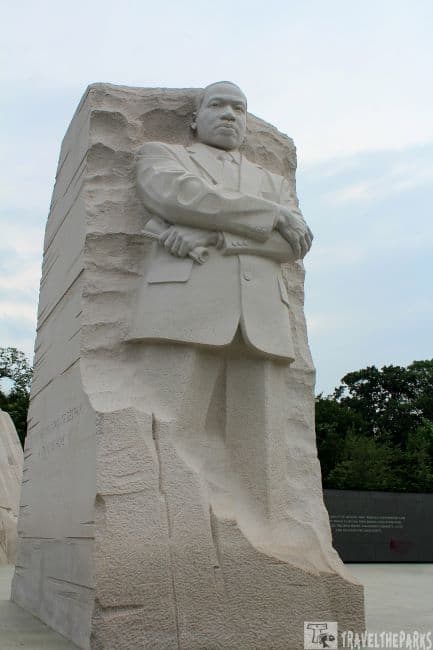 The Stone of Hope at the Martin Luther King Jr. Memorial-Statue of him in a suit with arms crossed, carved from stone.