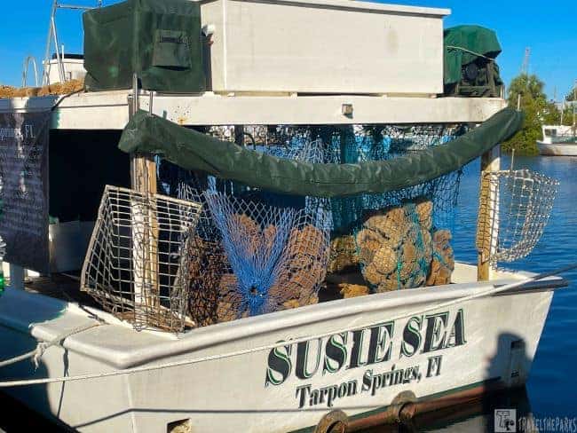 A boat named "Susie Sea" in Tarpon Springs, FL, with blue nets filled with natural sponges.