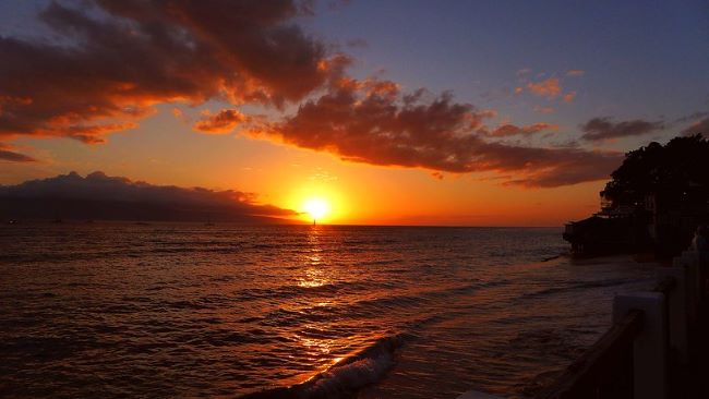 Sunset over the Kāʻanapali beach in Maui with vibrant colors and gentle waves near the shore.