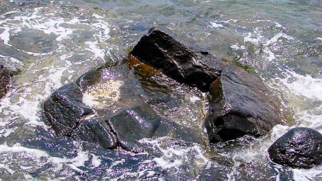 Hauola Stone in Lahina: Jagged rocks surrounded by swirling seawater.


