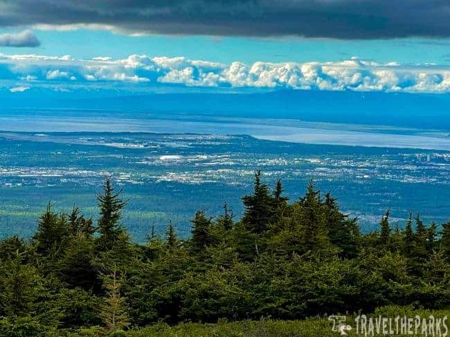 Flattop Mountain Scenic view of forested hills and distant Anchorage under a cloudy sky.