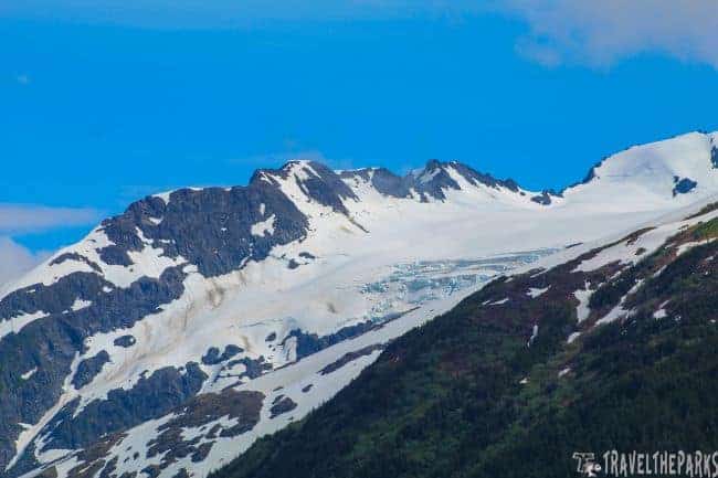 Portage Pass with snow-covered mountains and rocky outcrops under an overcast sky.