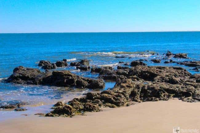 Black Rocks Little Talbot Island A sandy beach with rocky formations extending into a calm ocean under a clear blue sky.