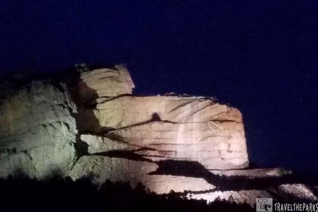 Crazy Horse Memorial illuminated at night against a dark sky.
