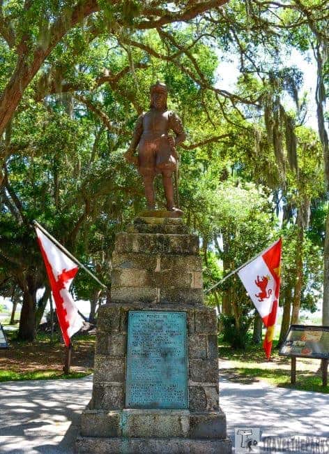 Statue on a stone pedestal with flags and trees in a park.

Transcribed Text:

JUAN PONCE DE LEON DISCOVERER OF FLORIDA […] MARCH 1513 THIS LAND WHICH HE CALLED LA FLORIDA ESTABLISHING A RIGHT OF POSSESSION UNDER THE SOVEREIGNTY OF THE CROWNS OF SPAIN AND CASTILE FROM WHICH THIS COUNTRY DERIVES THE NAME OF FLORIDA THIS MEMORIAL ERECTED BY PONCE DE LEON’S DESCENDANTS IN THE RICHEST AGRICULTURAL SECTIONS OF SPAIN AUGUST 1909.
