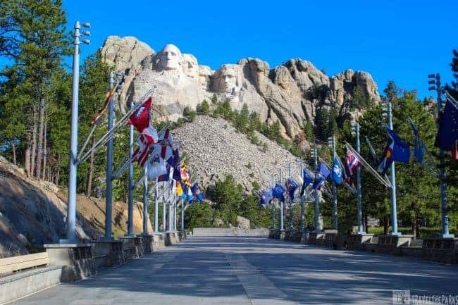 Avenue of Flags leading to Mount Rushmore, with state flags and blue sky.