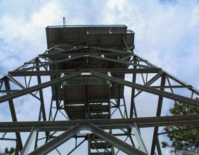 Rankin Trail Fire Tower view from below of a tall steel observation tower against a cloudy sky.

