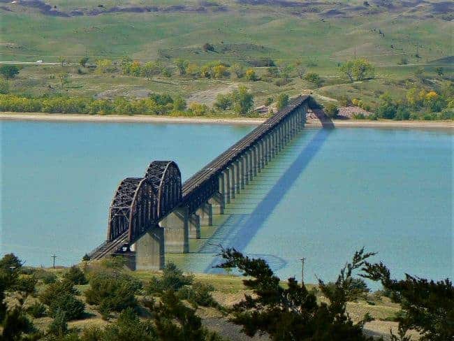 Chamberlain Pontoon railway bridge crossing the Missouri River with steel arches and concrete piers, surrounded by autumn foliage.