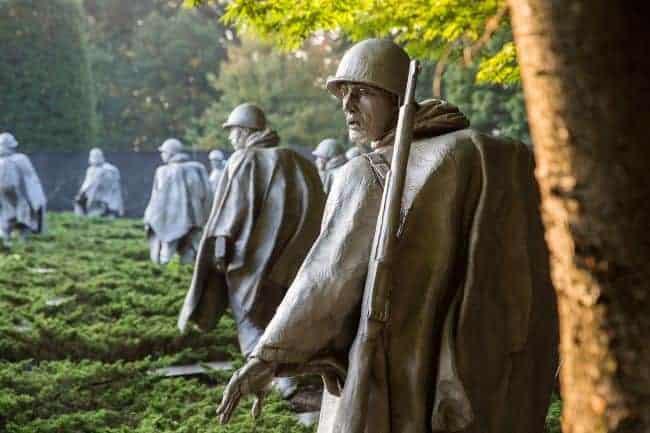 Korean Ware memorial-Statues of soldiers in ponchos with rifles on their shoulders, walking through bushes.