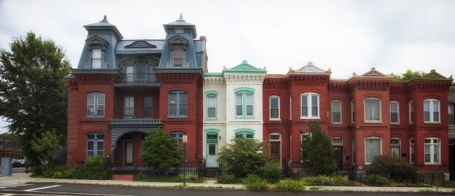 Row of six colorful attached houses with distinct architectural details.